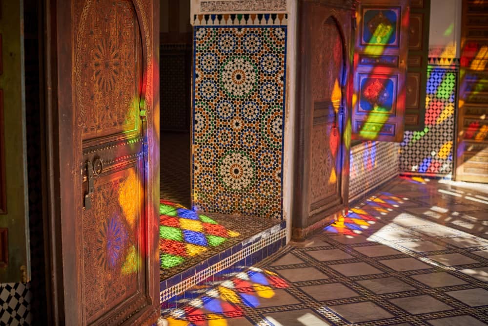 Intricate carved cedarwood door and stained glass detail inside Bahia Palace, Marrakech