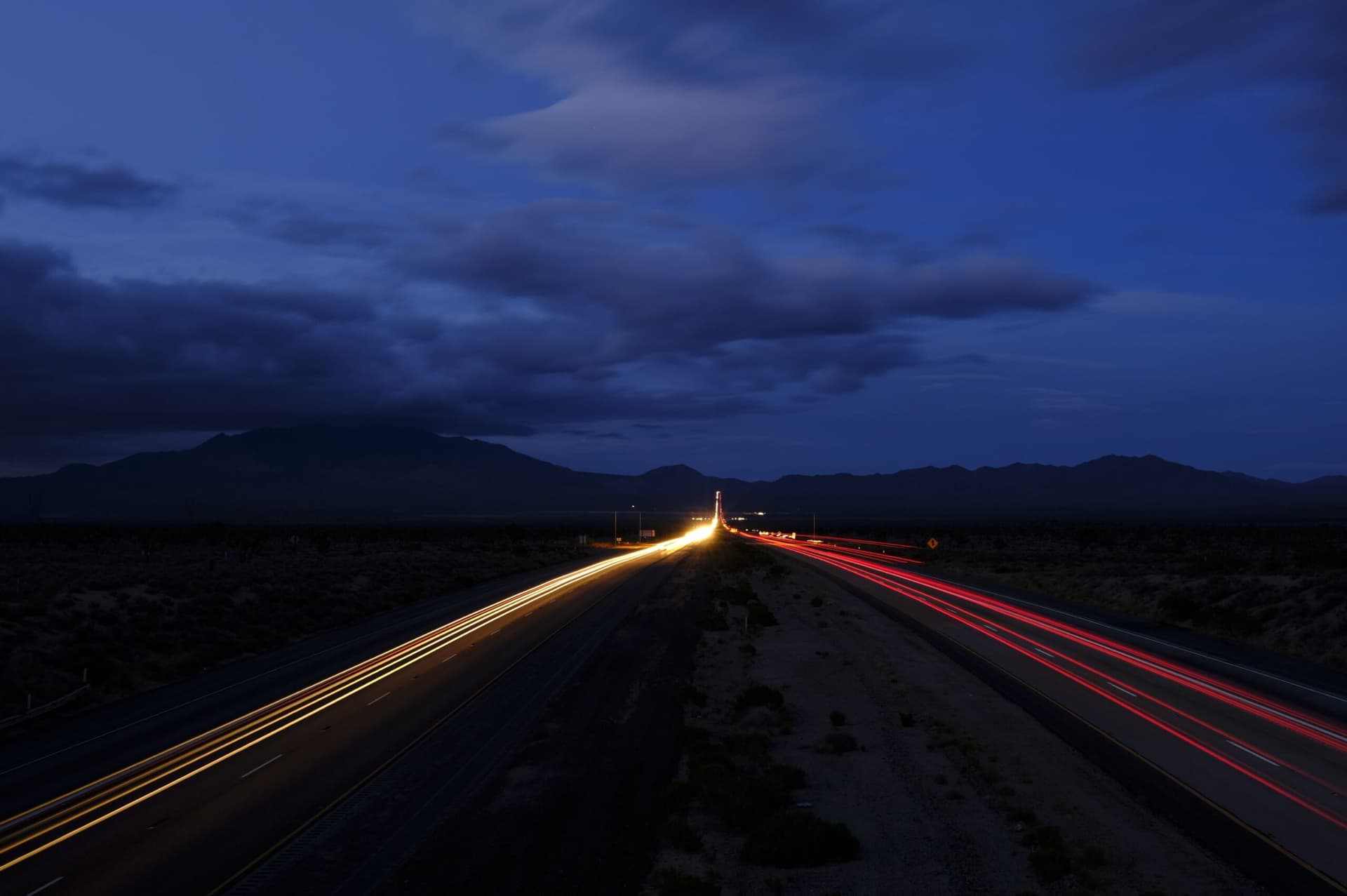 Car headlights and taillights streaking along a desert road at night on the drive back to Marrakech