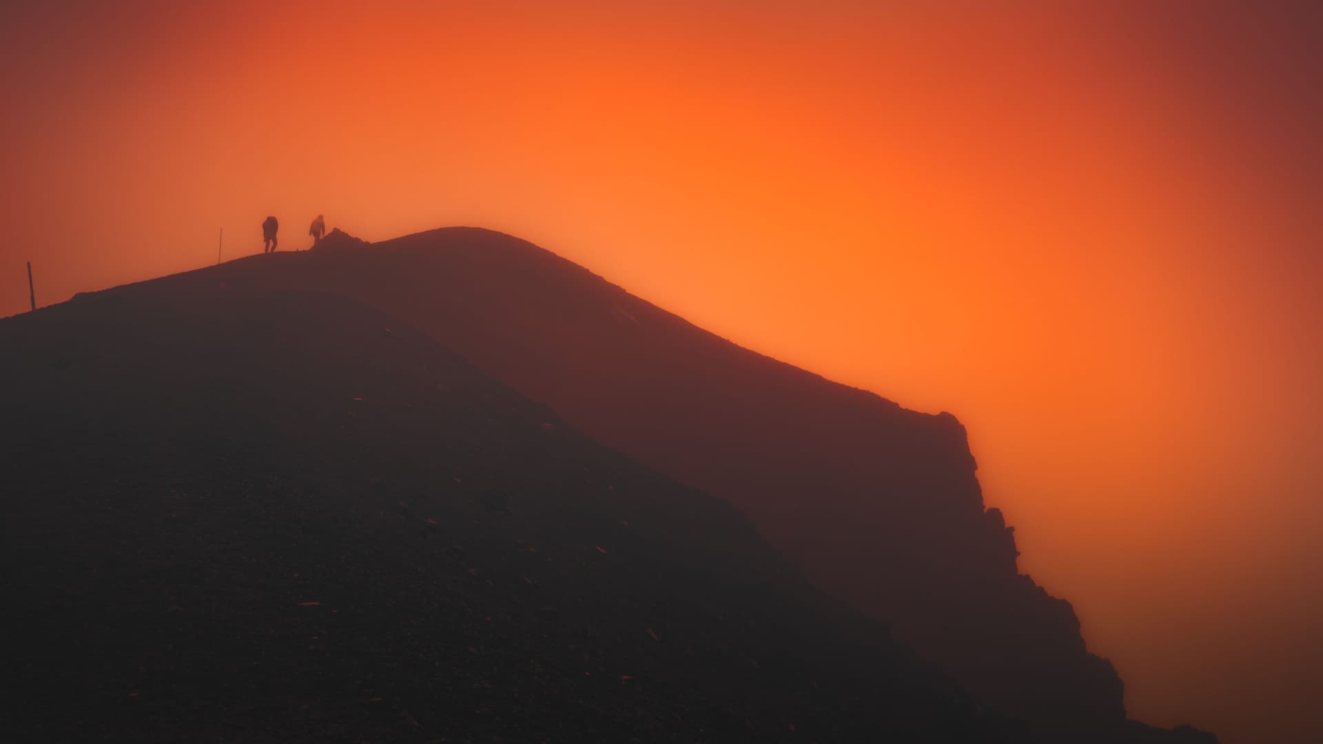 Hikers silhouetted on a mountain ridge at sunrise during the pre-dawn ascent to Tizi n'Toubkal pass
