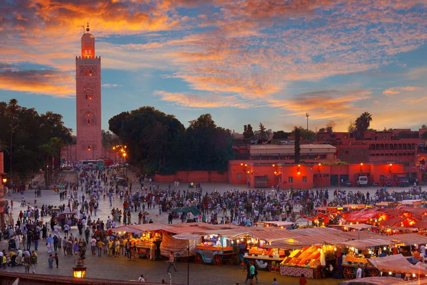 Jemaa el-Fna square in Marrakech at dusk with the Koutoubia Mosque minaret behind