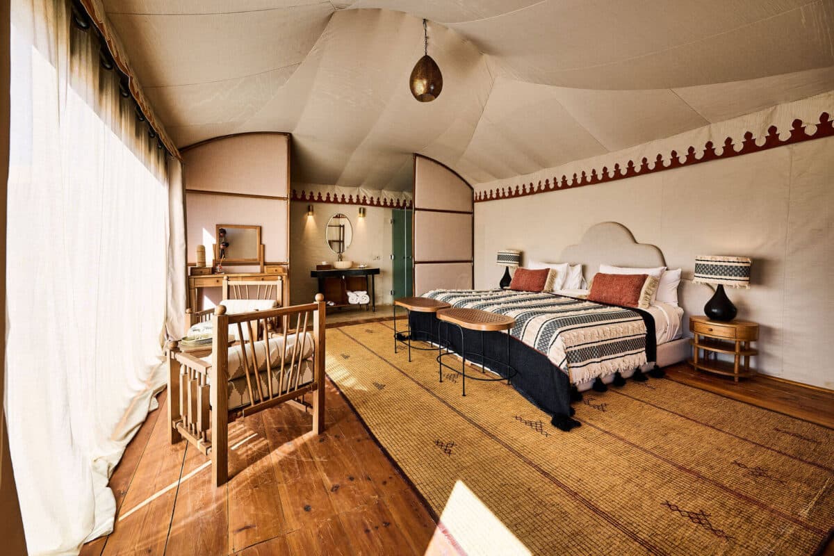 The interior of a luxury desert camp tent in Erg Chebbi with rugs and a made bed