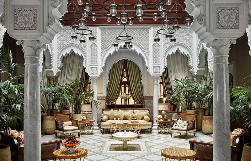 The courtyard of a traditional Moroccan riad with zellige tilework and a central fountain