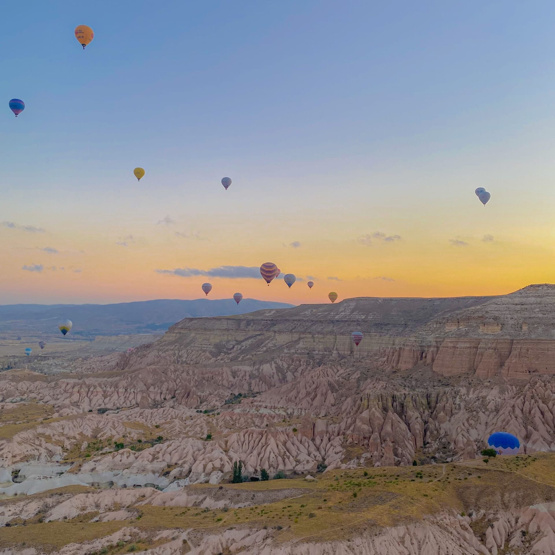 Aerial view from a hot air balloon basket over hills bathed in sunrise light