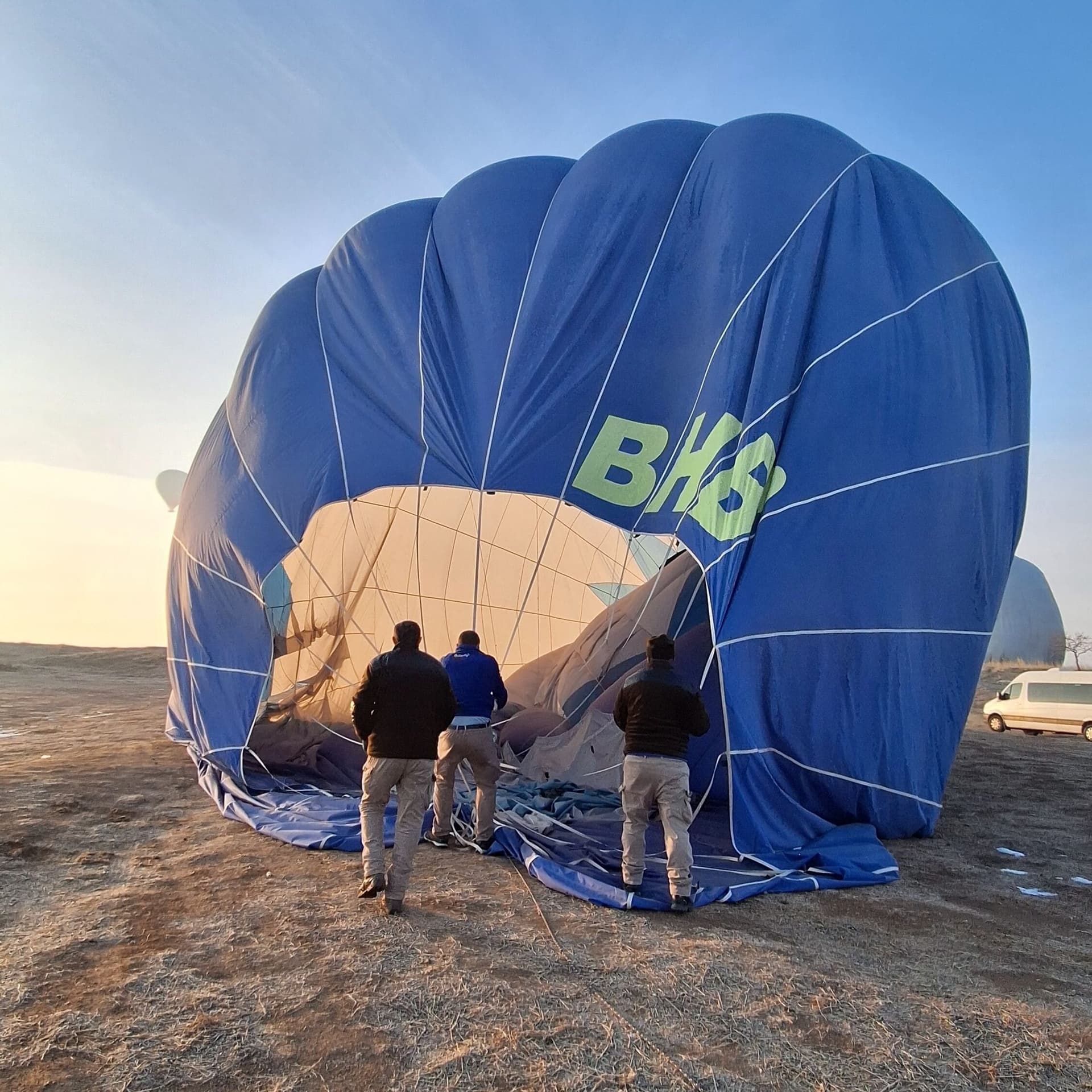 Ground crew inflating a hot air balloon envelope with fans before sunrise launch