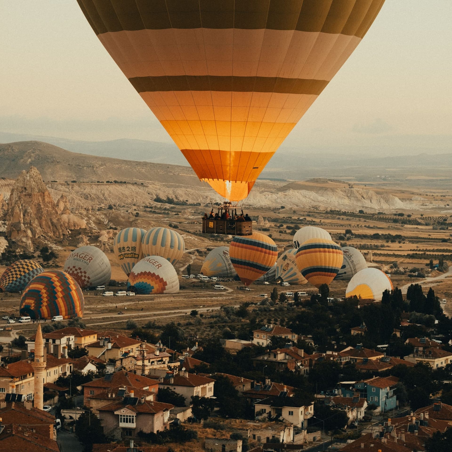 Hot air balloon in flight low over a traditional adobe village rooftop