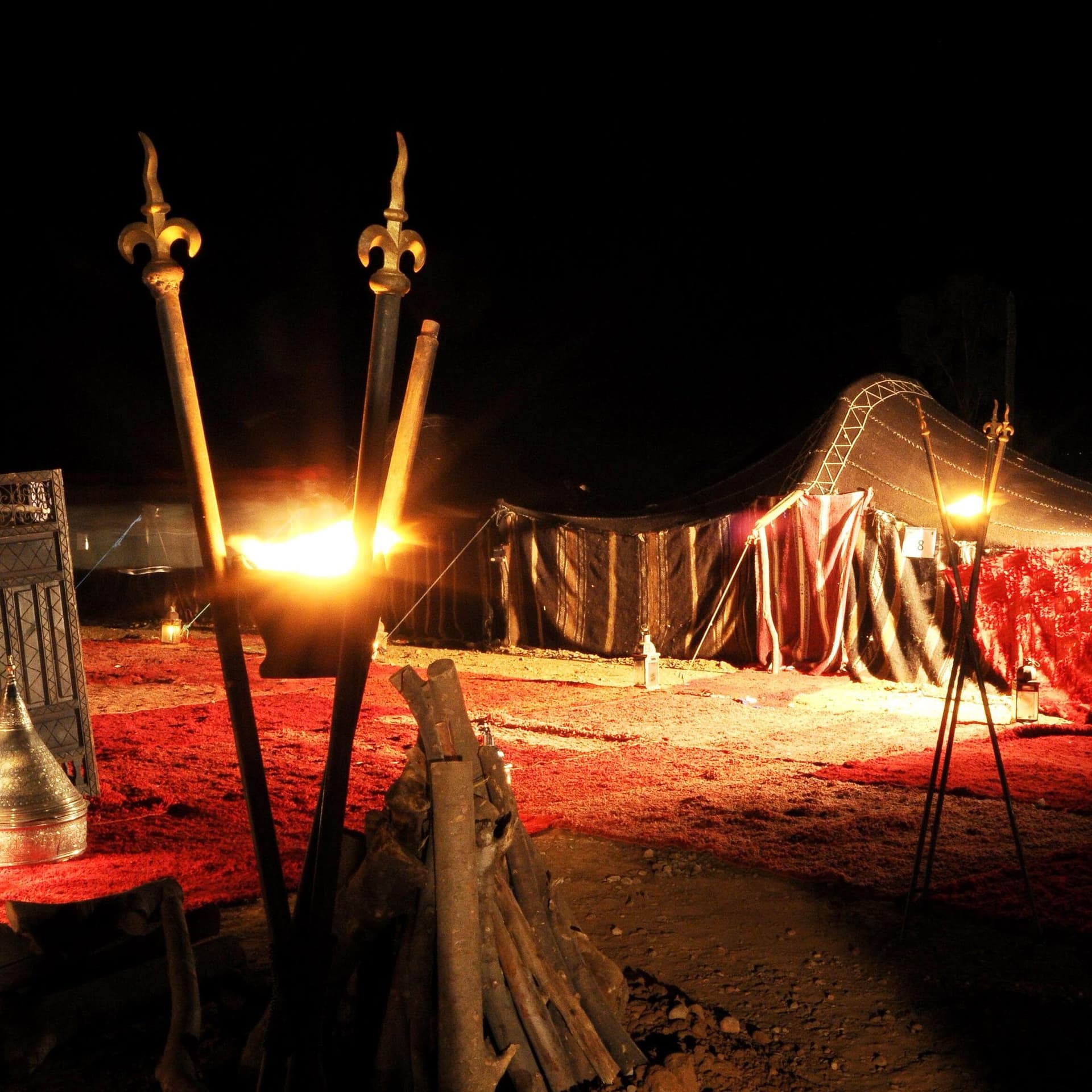 Traditional Berber tent lit by torches and lanterns during a candlelit desert dinner at night