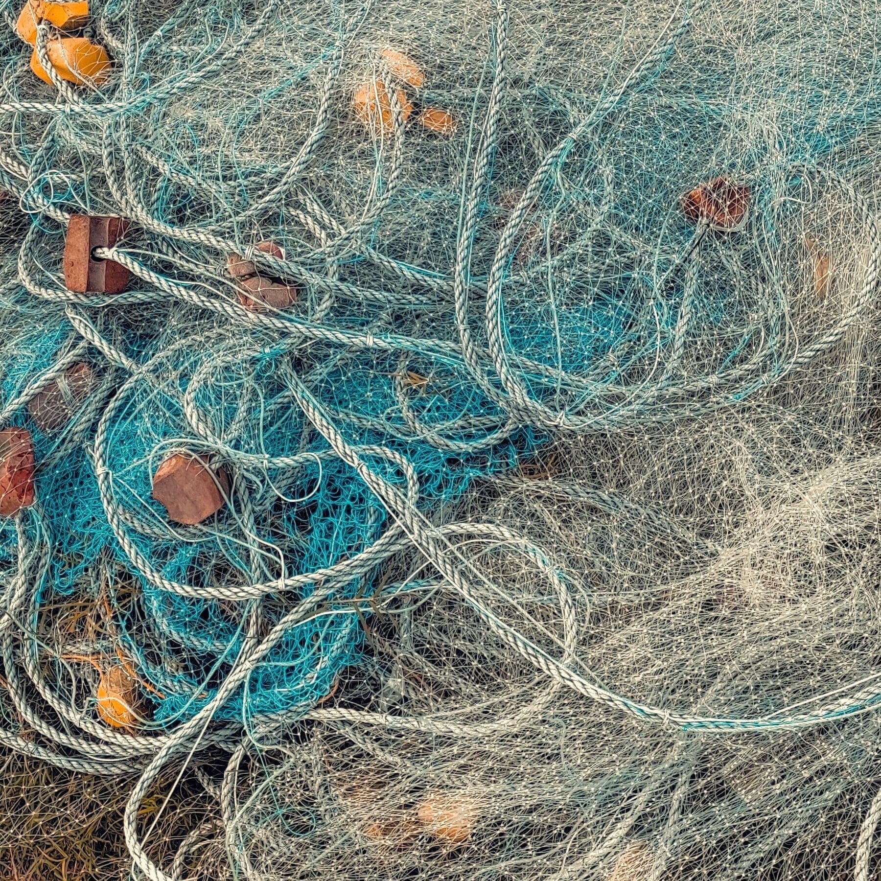 Moroccan fishermen mending fishing nets beside a wooden boat at the harbor
