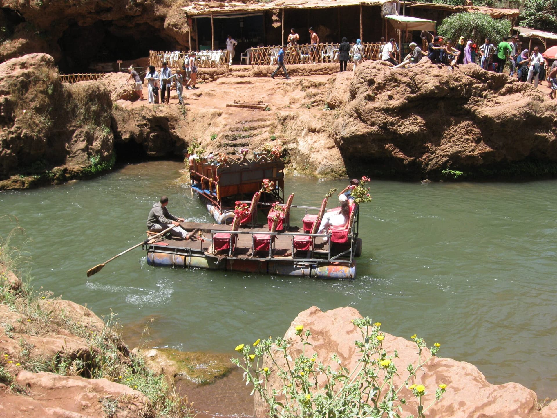 Small wooden flouka boat carrying visitors through the misty spray at the base of Ouzoud Falls