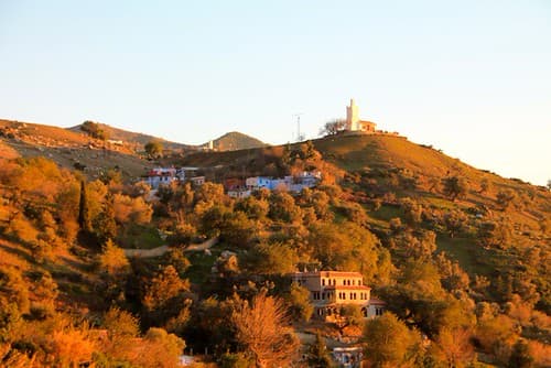 Panoramic view of Chefchaouen blue city from the Spanish Mosque viewpoint at golden hour