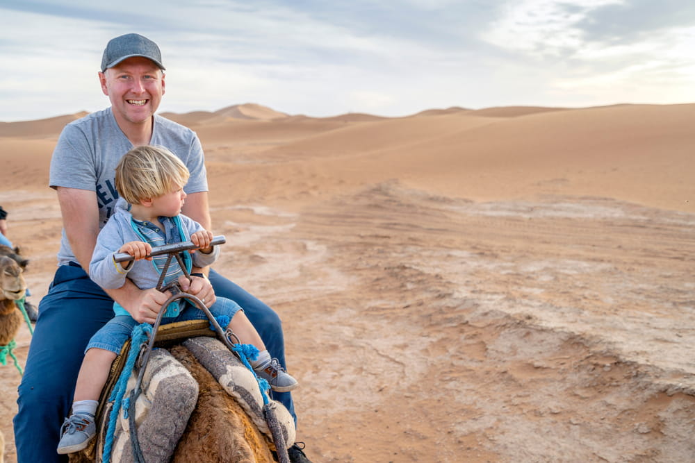 Father And Son Riding A Camel